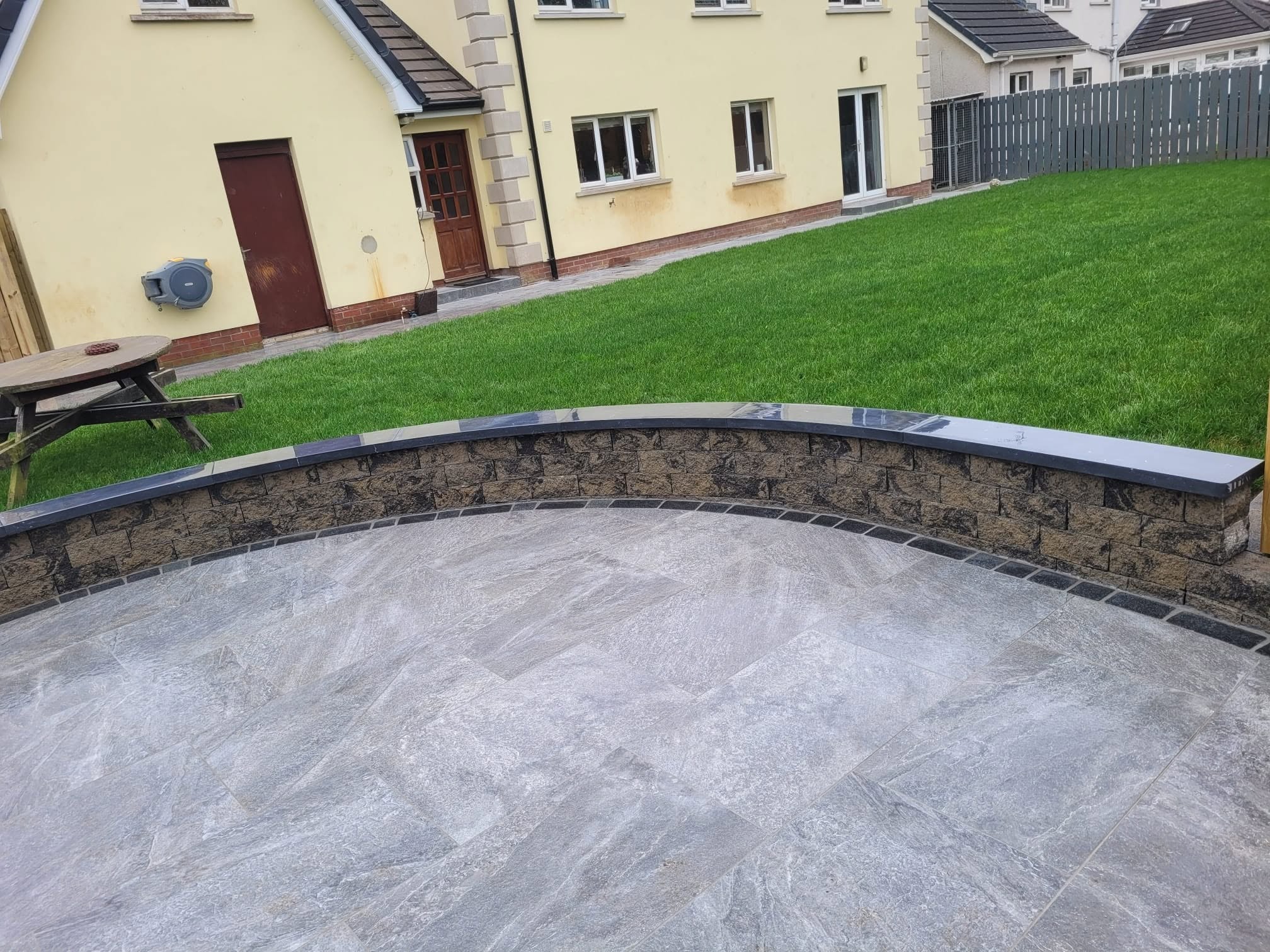 Curved back garden wall enclosing patio area