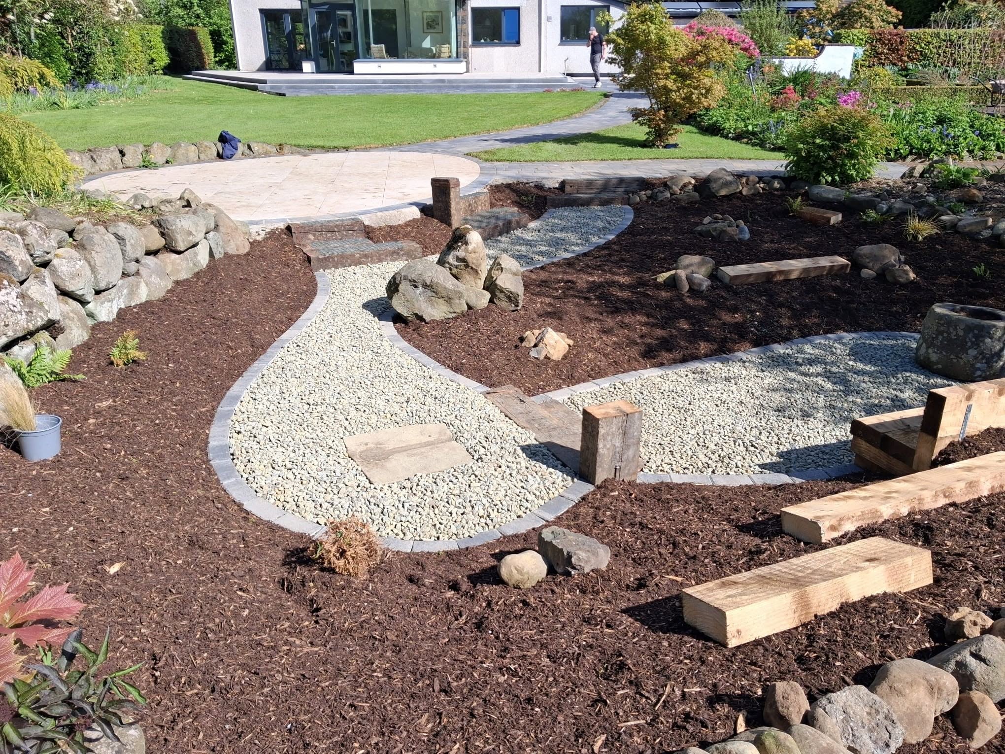 Stone and rockery area with wood chippings in garden of large home